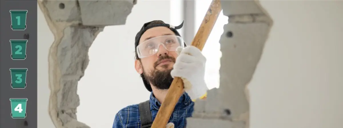 Image of a construction worker with a sledgehammer breaking through a wall