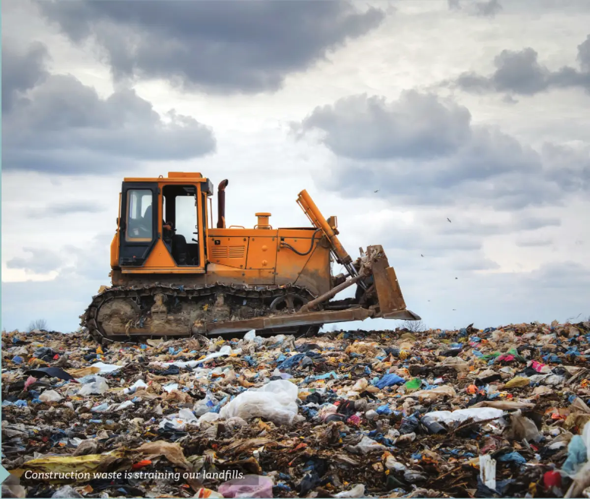 Photograph showing a bulldozer operating on a large landfill site covered with mixed waste