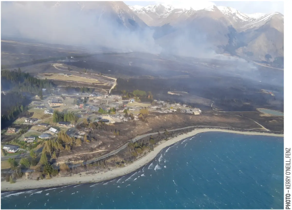 Aerial photo of a coastal settlement beside land burnt by a wildfire