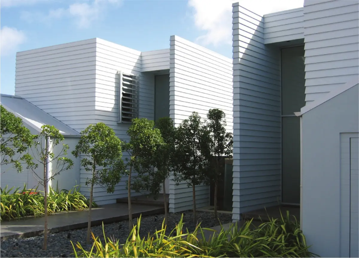 Modern residential buildings with white timber weatherboards and landscaped greenery