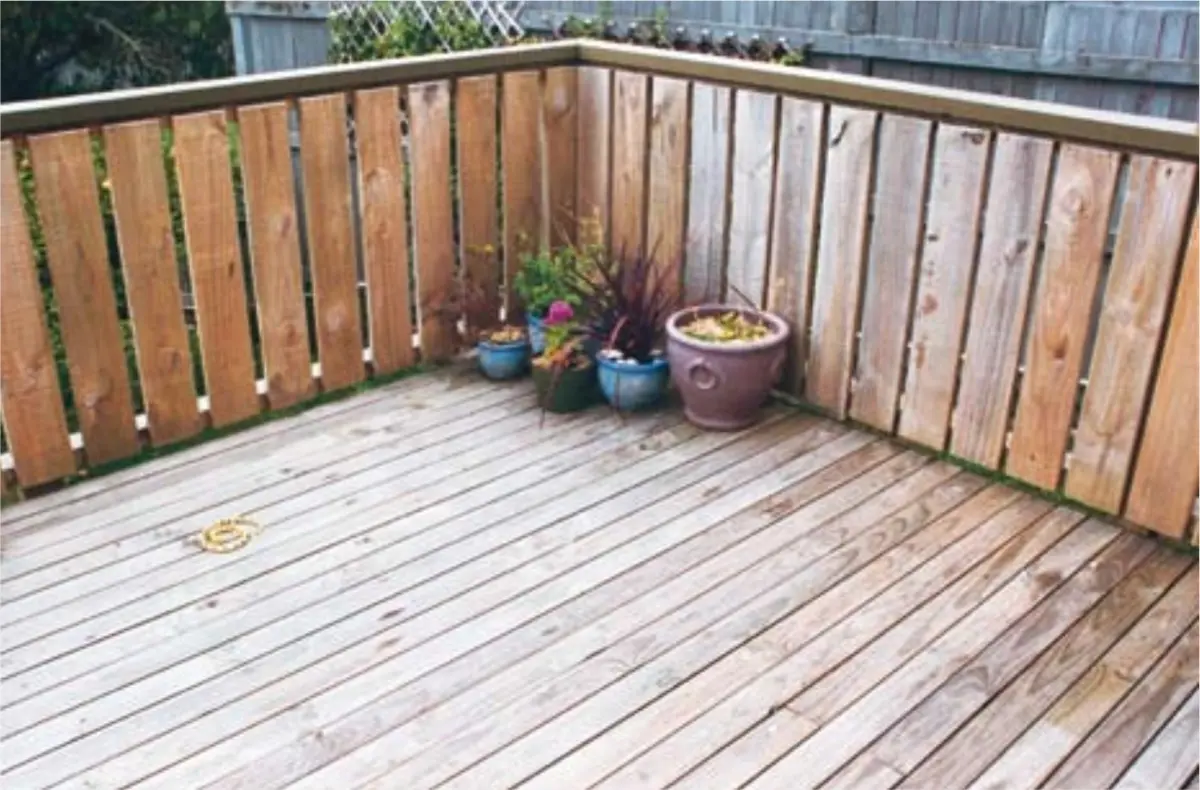 Photograph showing a timber deck with wooden balustrade and potted plants in a corner