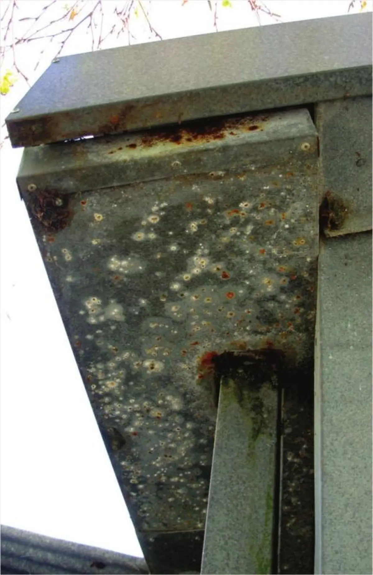 a photo of rust growing on the bottom of a metal gutter