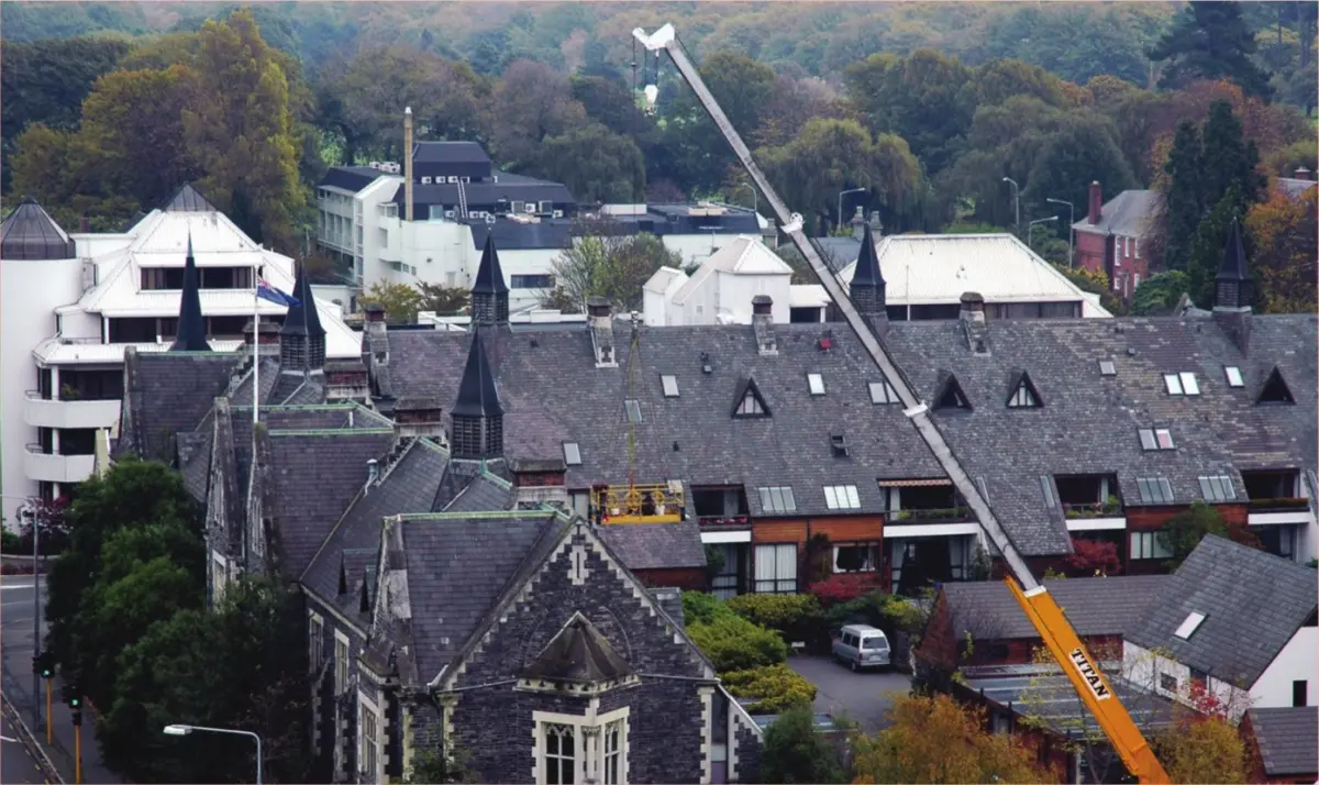 A photo of a crane reaching over the roof of an old building