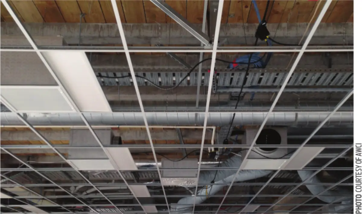 A photo of ceiling with its boards removed revealing pipes and wires
