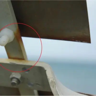 Photograph showing a close‑up of a metal flashing joint with a small white plastic spacer or fixing protruding between overlapping metal sections