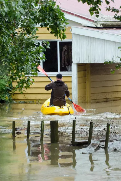 a kayaker paddling around a flooded house